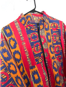 Bomber jacket with an allover red, orange and blue colorful Ikat print. Jacket has two front pockets and front zipper with elastic on wrists and waist. 