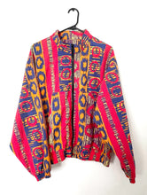 Load image into Gallery viewer, Bomber jacket with an allover red, orange and blue colorful Ikat print. Jacket has two front pockets and front zipper with elastic on wrists and waist. 